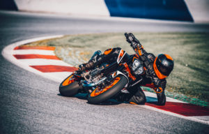 Motorradfahrer mit KTM-Motorrad in sportlicher Kurvenlage auf einer Rennstrecke.