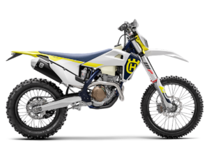 Husqvarna Enduro-Motorrad in weiß-blau-gelber Lackierung mit leistungsstarkem Motor und grobstolligen Reifen für Offroad-Abenteuer.