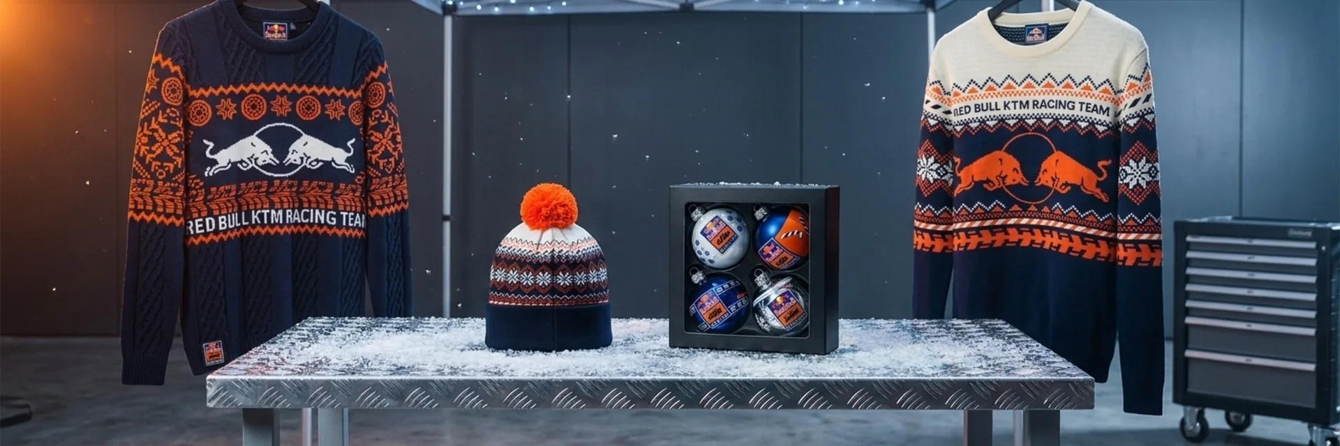 Red Bull KTM Winter Sweater, Wintermütze und Weihnachtskugeln auf einer verschneiten Werkbank in einer KTM-Rennwerkstatt