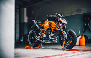 Ein hochwertiges KTM-Motorrad in leuchtendem Orange steht auf einem Motorradständer in einer modernen Werkstatt.